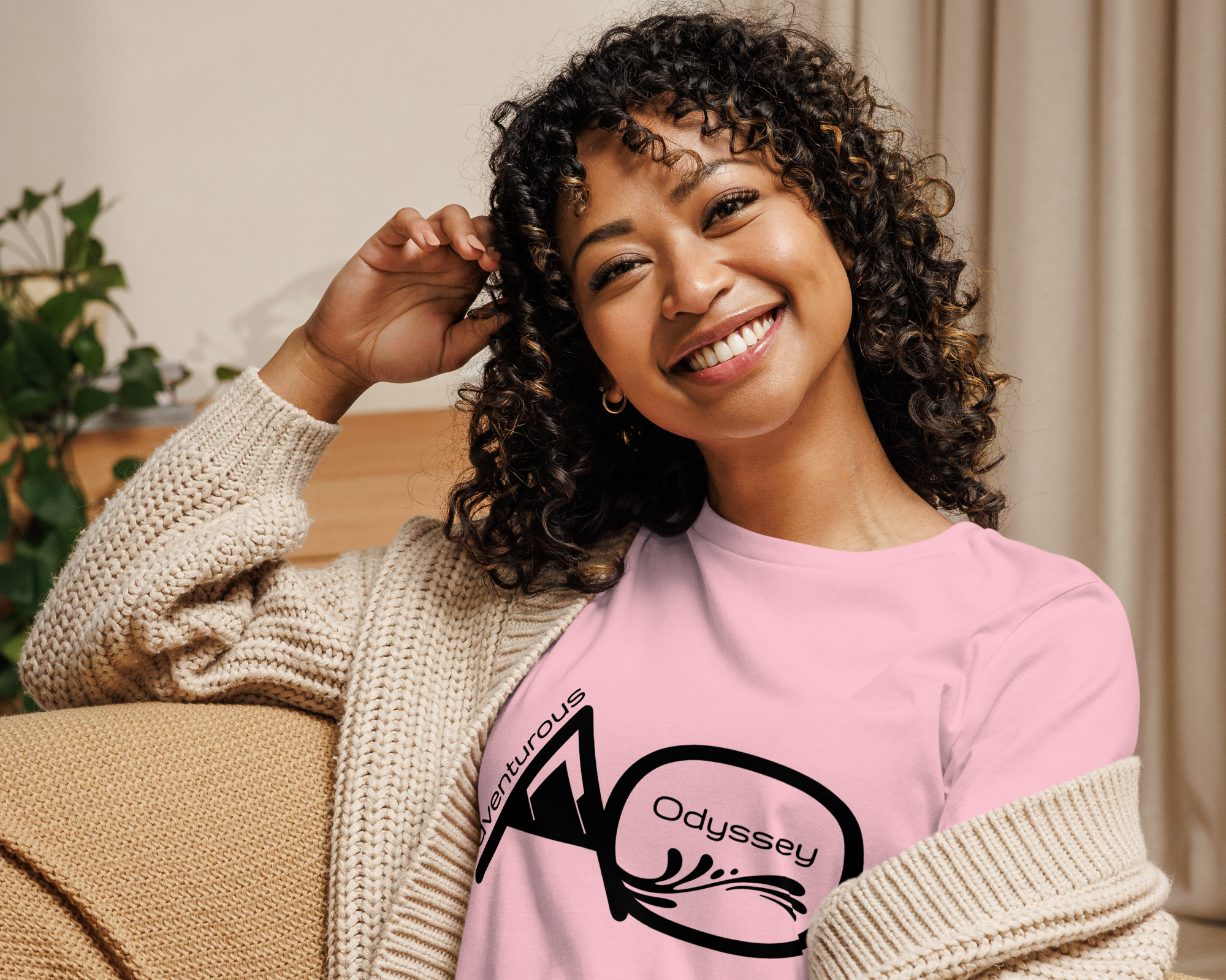 Woman wearing a pink sweatshirt with a logo, sitting on a couch.